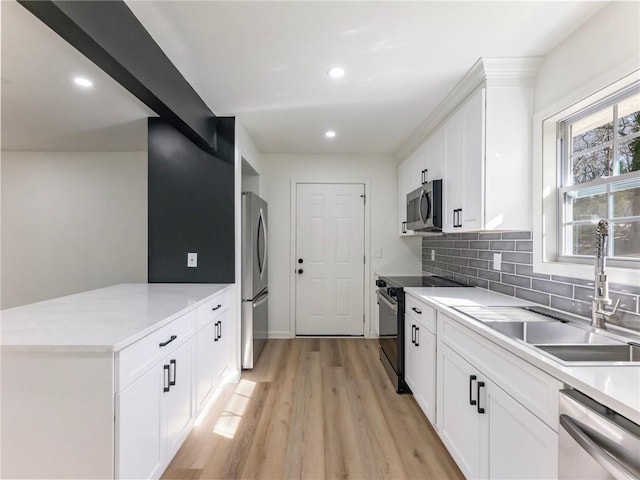 kitchen with recessed lighting, a sink, light wood-style floors, a peninsula, and appliances with stainless steel finishes
