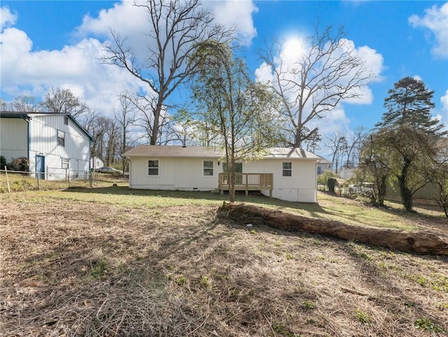 rear view of property featuring a yard, fence, and a deck