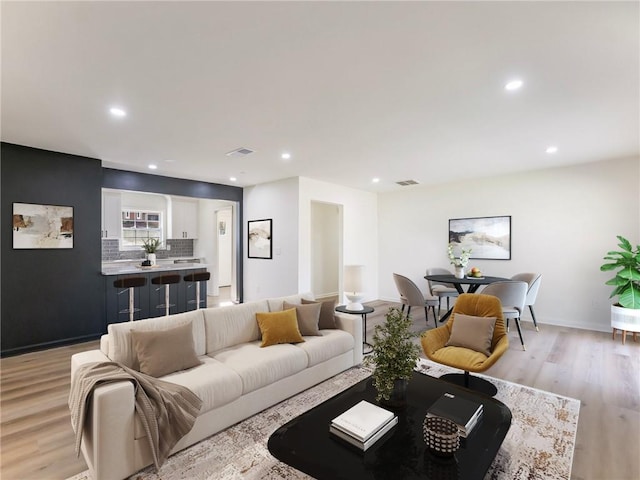 living area with recessed lighting, light wood-type flooring, visible vents, and baseboards