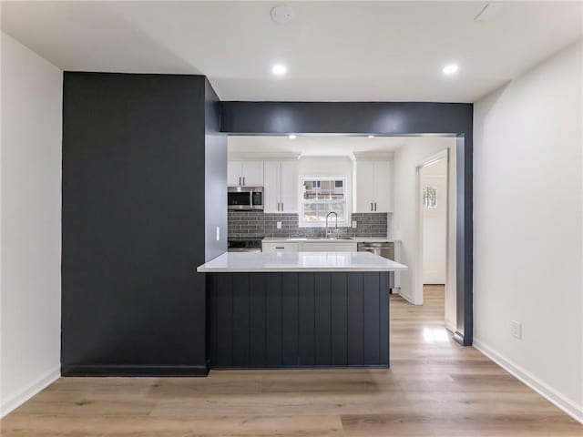 kitchen featuring tasteful backsplash, a sink, light countertops, white cabinets, and appliances with stainless steel finishes