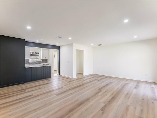 unfurnished living room with light wood-type flooring, baseboards, visible vents, and recessed lighting