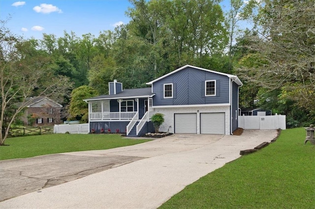 split level home featuring covered porch, a front yard, and a garage