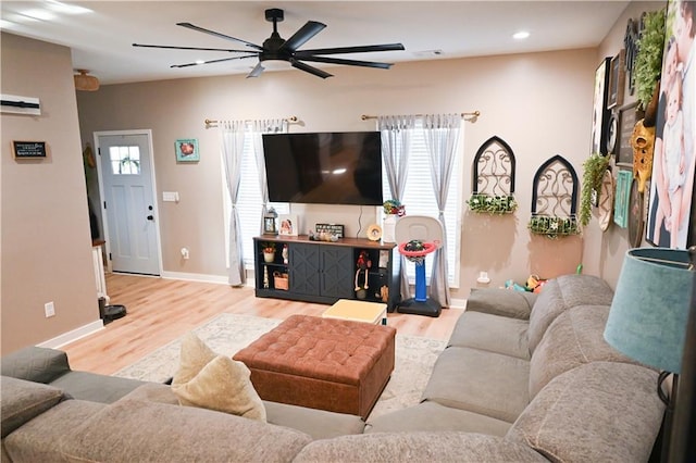 living area with baseboards, a ceiling fan, wood finished floors, and plenty of natural light