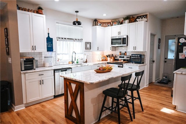 kitchen with white cabinets, a kitchen bar, stainless steel appliances, and a sink