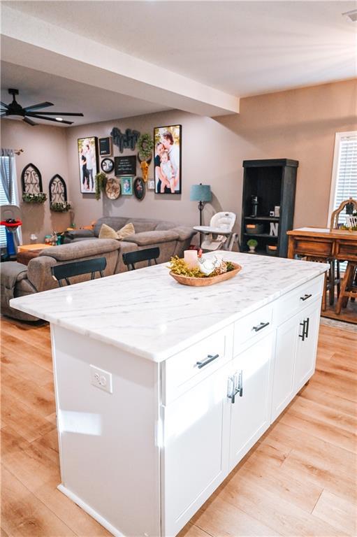 kitchen featuring white cabinets, open floor plan, a ceiling fan, and light wood-style flooring
