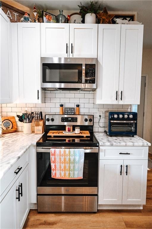 kitchen with white cabinets, stainless steel appliances, and light wood-style flooring