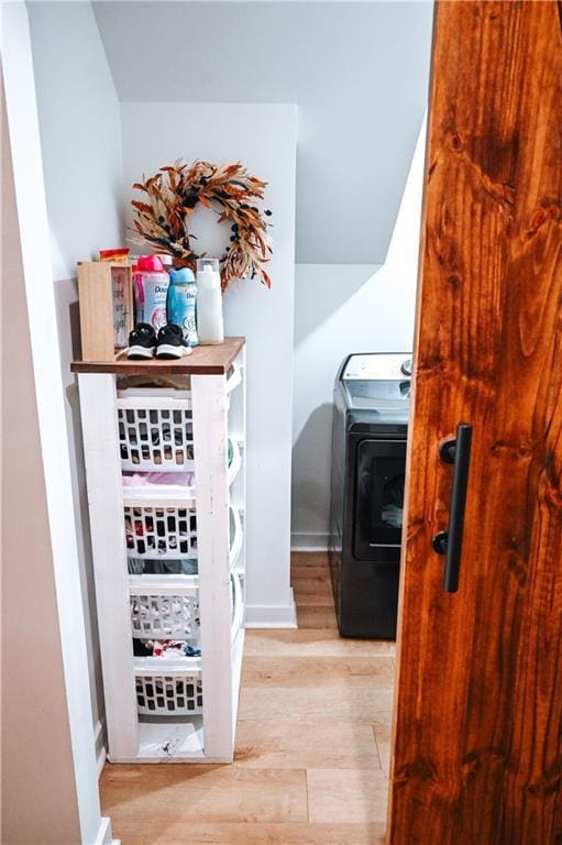 hallway featuring baseboards, wood finished floors, and washer / dryer