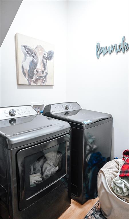 clothes washing area featuring washing machine and dryer, light wood-style flooring, and laundry area