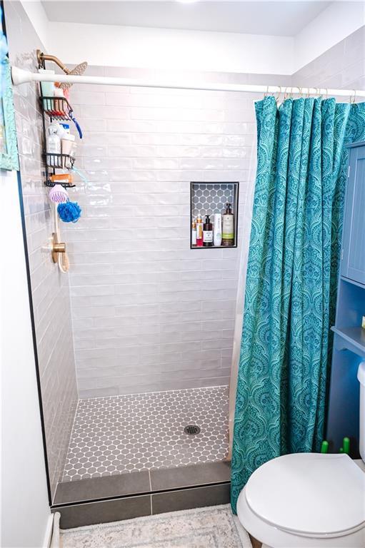 full bath featuring a tile shower and toilet