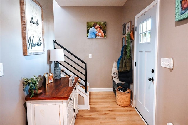 foyer with stairway, baseboards, and light wood-style flooring
