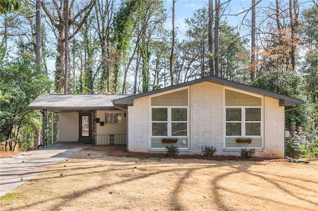 mid-century modern home with an attached carport, concrete driveway, and brick siding