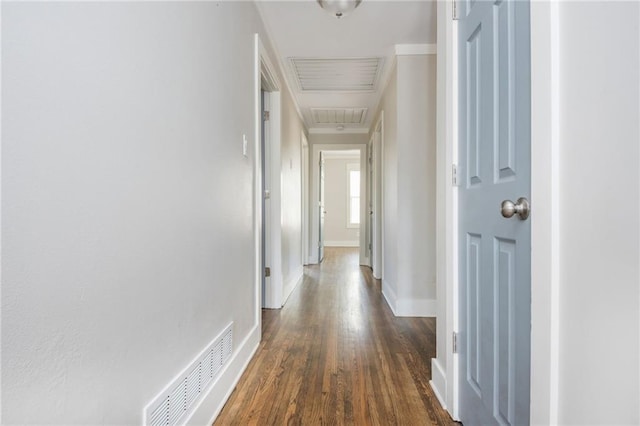 hallway with dark wood-type flooring, baseboards, and visible vents