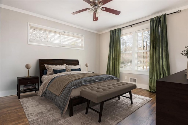 bedroom with visible vents, crown molding, baseboards, ceiling fan, and dark wood-style flooring