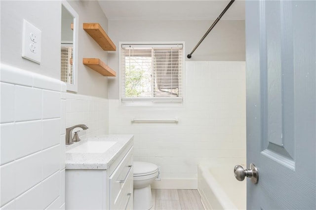 bathroom featuring vanity, a wainscoted wall, bathing tub / shower combination, tile walls, and toilet