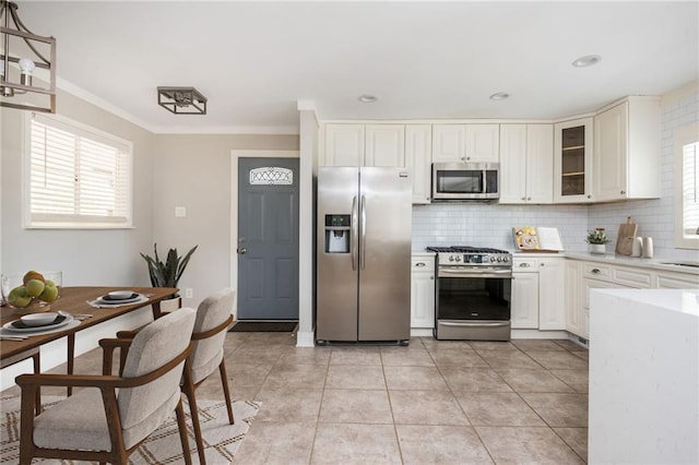 kitchen with backsplash, appliances with stainless steel finishes, crown molding, light countertops, and light tile patterned floors