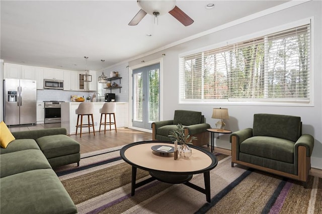 living area with light wood finished floors, recessed lighting, a ceiling fan, and ornamental molding