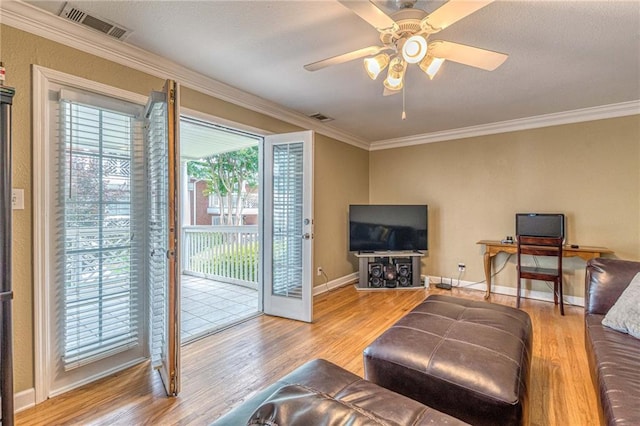 living room with ornamental molding, visible vents, and wood finished floors