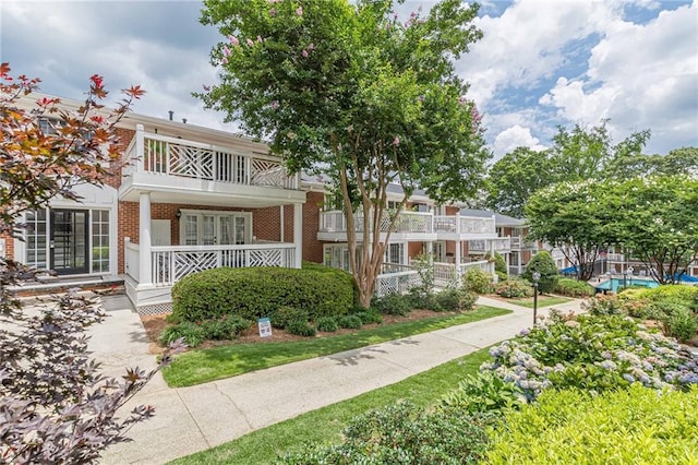 view of front of house featuring a balcony and brick siding