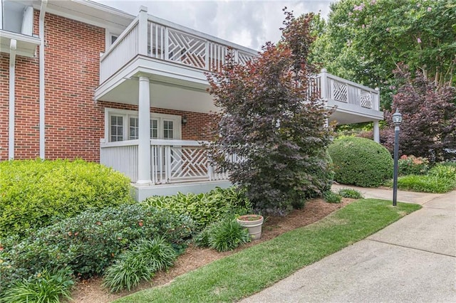 view of side of property with brick siding and a balcony