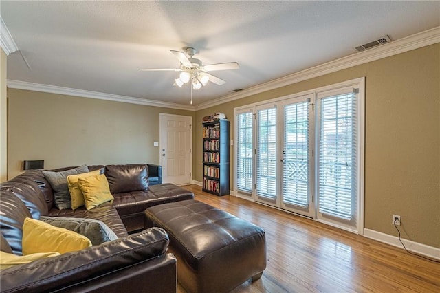 living room featuring a healthy amount of sunlight, crown molding, visible vents, and wood finished floors