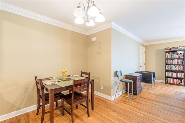 dining area with baseboards, crown molding, light wood-style flooring, and an inviting chandelier