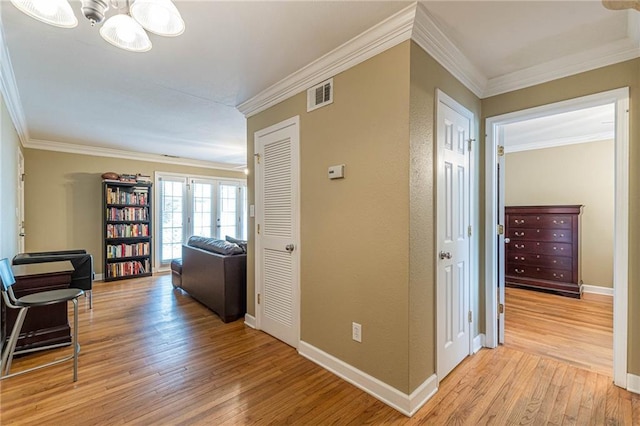 hall featuring french doors, crown molding, and light wood-style flooring