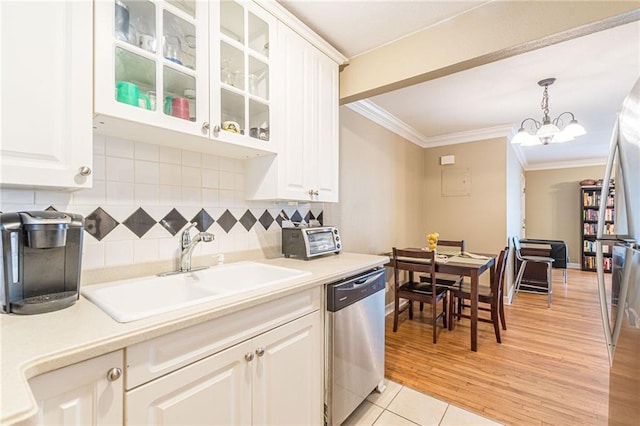 kitchen featuring glass insert cabinets, ornamental molding, stainless steel dishwasher, pendant lighting, and a sink