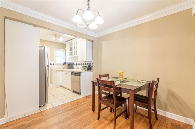 dining space with ornamental molding, baseboards, light wood finished floors, and an inviting chandelier