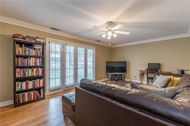 living room featuring crown molding, visible vents, ceiling fan, light wood-type flooring, and baseboards