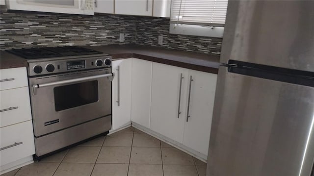 kitchen featuring light tile flooring, stainless steel appliances, white cabinets, and backsplash