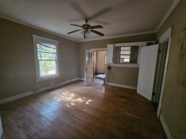 unfurnished bedroom with crown molding, ceiling fan, and dark hardwood / wood-style flooring