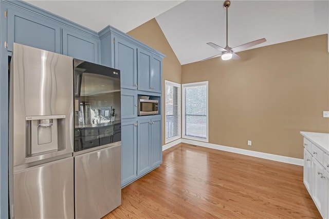 kitchen featuring blue cabinetry, lofted ceiling, light wood-type flooring, ceiling fan, and stainless steel appliances