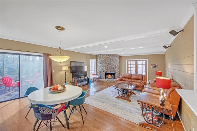 living room with ornamental molding, a fireplace, light hardwood / wood-style floors, and beam ceiling