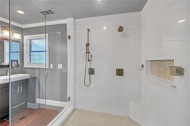 bathroom with vanity, hardwood / wood-style floors, a shower with shower door, and ornamental molding