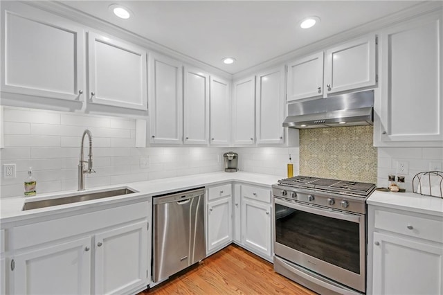 kitchen featuring sink, white cabinetry, stainless steel appliances, light hardwood / wood-style floors, and backsplash