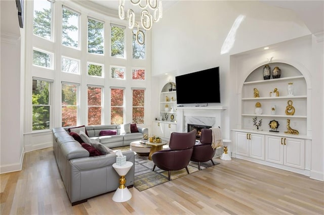 2461 Oak Grove Ests NE, Atlanta, GA 30345 - living room with light wood-style floors, a fireplace, a towering ceiling, built in shelves, and baseboards