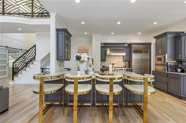 2461 Oak Grove Ests NE, Atlanta, GA 30345 - kitchen featuring built in appliances, wall chimney range hood, decorative backsplash, light countertops, and ornamental molding