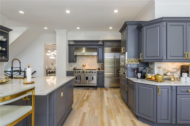 2461 Oak Grove Ests NE, Atlanta, GA 30345 - kitchen featuring built in appliances, wall chimney exhaust hood, tasteful backsplash, light wood-type flooring, and light stone counters