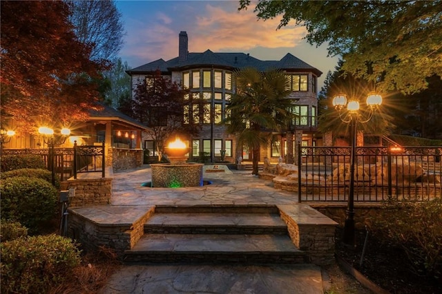 2461 Oak Grove Ests NE, Atlanta, GA 30345 - back of property at dusk featuring a chimney and a patio