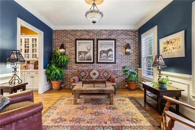 sitting room with brick wall, crown molding, wood finished floors, and a wainscoted wall