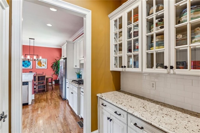 kitchen with stainless steel appliances, a chandelier, light wood-type flooring, white cabinetry, and ornamental molding