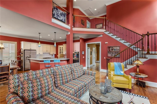 living room featuring crown molding, light wood-type flooring, stairway, baseboards, and recessed lighting