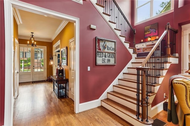 stairs featuring crown molding, a chandelier, baseboards, and wood finished floors
