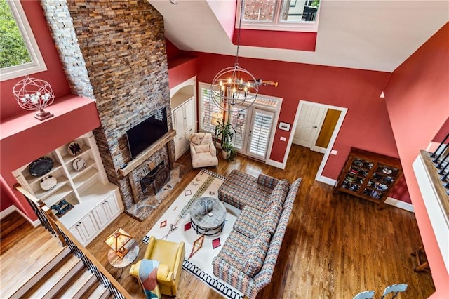 living room with a chandelier, wood finished floors, a fireplace, high vaulted ceiling, and baseboards