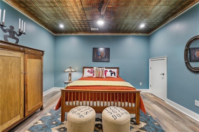 bedroom featuring an ornate ceiling, crown molding, wood finished floors, baseboards, and recessed lighting