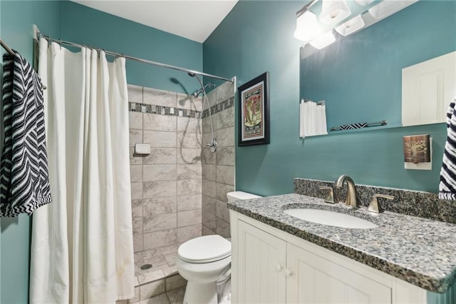 full bathroom featuring toilet, a tile shower, and vanity
