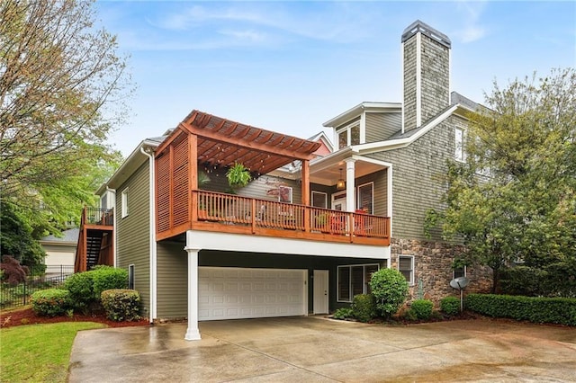 back of property featuring a balcony, concrete driveway, an attached garage, stone siding, and fence