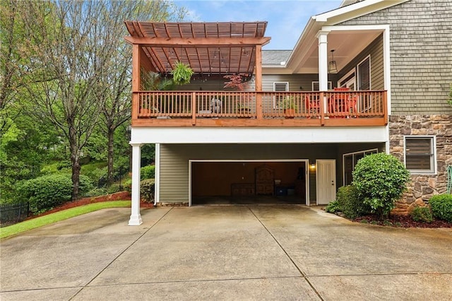 back of house with an attached garage, a balcony, concrete driveway, and stone siding