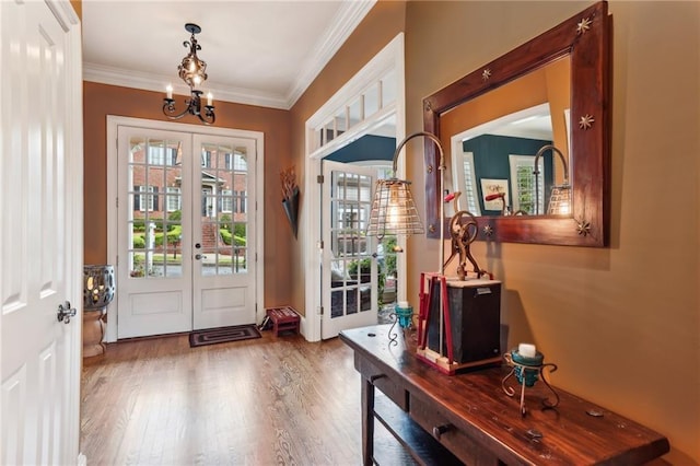 doorway to outside with french doors, wood finished floors, ornamental molding, and a chandelier