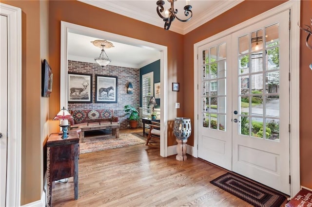 entrance foyer with french doors, ornamental molding, wood finished floors, a chandelier, and baseboards